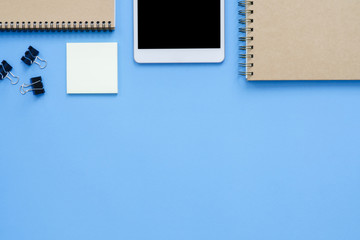 Office desk working space - Flat lay top view mockup photo of a working space with tablet, notebook, coffee and stationary on blue pastel background. Pastel blue color copy space working desk concept.