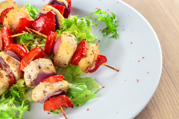 chicken fillet kebabs with roasted peppers, onions and lettuce on wooden skewers are on the plate
