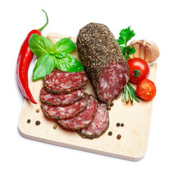 Dried organic salami sausage covered with pepper on wooden serving board