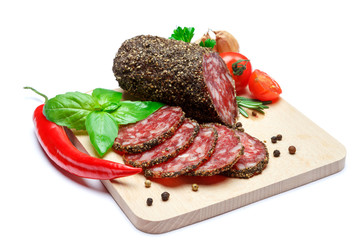 Dried organic salami sausage covered with pepper on wooden serving board