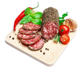Dried organic salami sausage covered with pepper on wooden serving board