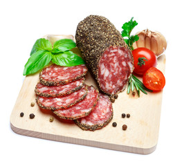 Dried organic salami sausage covered with pepper on wooden serving board