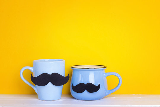 Two blue mug with a mustache on yellow background. Copy space.