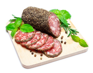 Dried organic salami sausage covered with pepper on wooden serving board