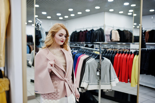 Elegance blonde girl in coat at the store of fur coats and leather jackets.
