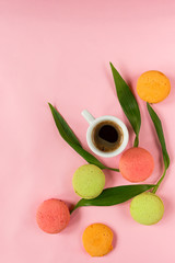 Creative layout. A cup of espresso, colorful macaroons and flowers on a pink background. Pastel colors. Place for text. Сoncept. Flat lay