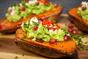 ealthy dinner - Baked sweet potatoes served with guacamole, feta cheese and pomegranate