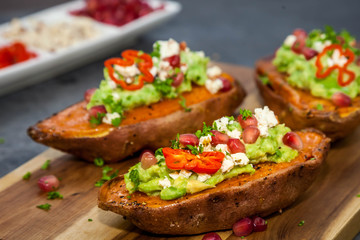 ealthy dinner - Baked sweet potatoes served with guacamole, feta cheese and pomegranate