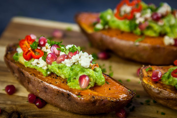 Healthy dinner - Baked sweet potatoes served with guacamole, feta cheese and pomegranate