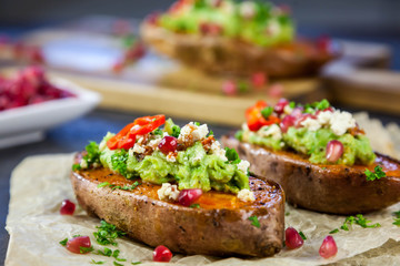Healthy dinner - Baked sweet potatoes served with guacamole, feta cheese and pomegranate