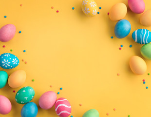 Happy Easter! Yellow background with colorful easter eggs. Top view with copy space.