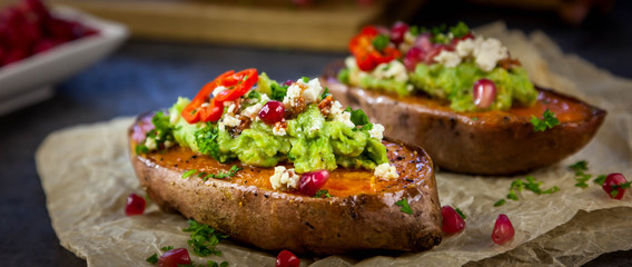 Healthy food - Baked sweet potatoes served with guacamole, feta cheese and pomegranate