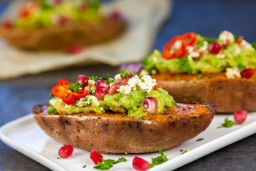 Healthy food - Baked sweet potatoes served with guacamole, feta cheese and pomegranate