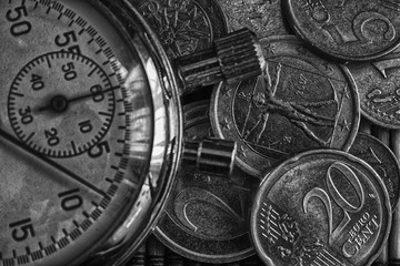 Stopwatch and pile of coins on wooden table background