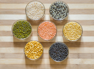 Seven bowls of lentils on a chopping board