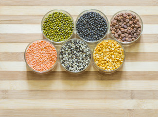 Six bowls of lentils on a chopping board