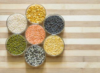 Seven bowls of lentils on a chopping board