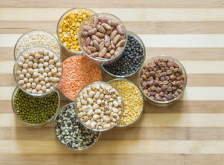 Eleven bowls of lentils and legumes on a chopping board
