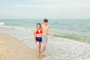 Two teenagers: a girl and a boy with blond hair, dressed in a sw