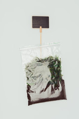top view of ziplock plastic bag with dried plants, soil and blackboard isolated on white, earth day concept