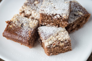 Brownie stack, closeup chocolate cake in white plate on rustic wooden table