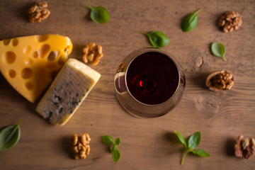 Red wine and cheese on wooden table background. Cheese appetizer selection or wine snack set. Glass and bottle of wine. overhead