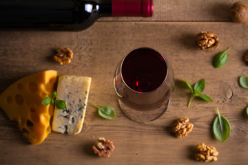 Fototapeta na wymiar Red wine and cheese on wooden table background. Cheese appetizer selection or wine snack set. Glass and bottle of wine. overhead