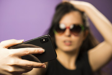 Young Woman Make Selfie in Sunglasses on Purple Background. Photo in Googles on the Latest Iphone X