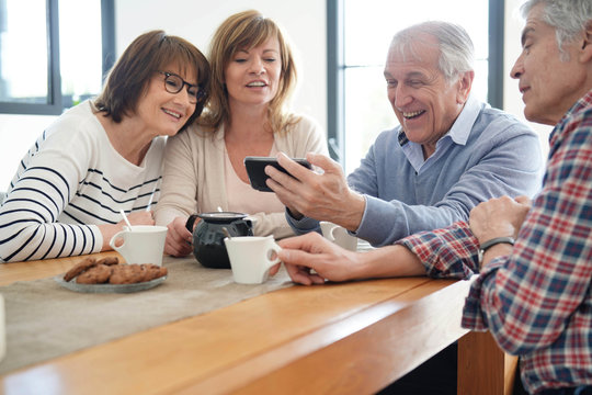 Group of senior friends looking at pictures on smartphone