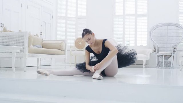 Graceful ballerina practicing ballet in white studio, slow motion
