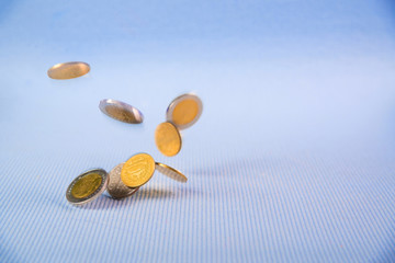 Falling coins money on blue background, business wealth concept.