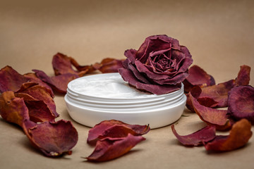 cosmetic cream with a withered rose and withered petals. The concept of using substandard cosmetics
