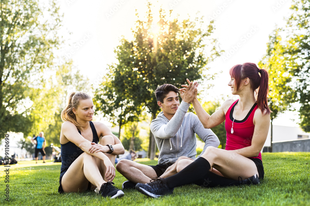 Wall mural Group of young runners resting in a park.