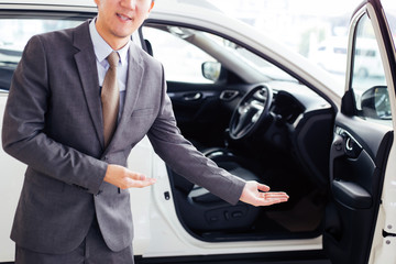 Young chauffeur in business suit welcoming rich and wealthy client on board - rich lifestyle taxi car transportation concept.