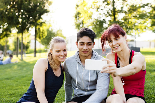 Group of young runners with a smartphone in a park.