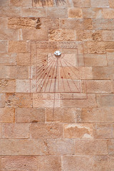 View of an old sundial located on an ancient wall. Roman numbers written on the rectangular board.