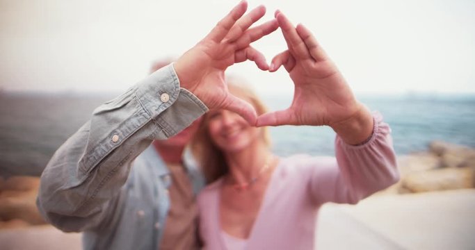 Romantic senior couple making a heart shape with their hands