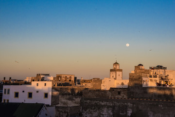 Full moon rising during sunset mosque in Essaouira, Morocco