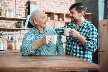 Happy nice father and son having tea