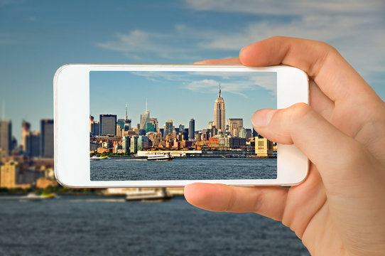 Closeup of a hand with smartphone taking a picture of  Manhattan skyline, New York USA