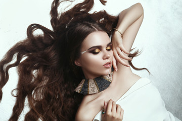 Beautiful model with creative makeup is deeply emotionally posing in a dark studio