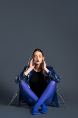 Girl wearing transparent raincoat and blue pantyhose sitting on dark background