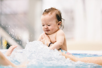 Little baby girl splashing in the water.