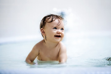Fototapeta na wymiar Laughing girl sitting in a shallow pool