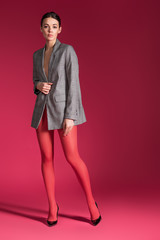 Fototapeta premium Sensual woman in red nylon tights wearing grey jacket on red background