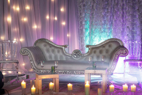 Rich silver sofa stands among shiny candles in the place arranged for wedding photos