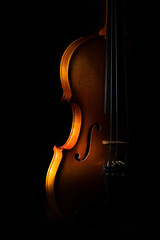 Violin detail on a black background between light or shadows