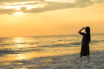 Fototapeta premium silhouette of a woman looking sunset on the beach
