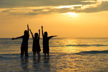 silhouette happy three woman on the sunset beach