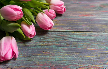 Border from bright pink tulips flowers on wooden background. Selective focus, place for text